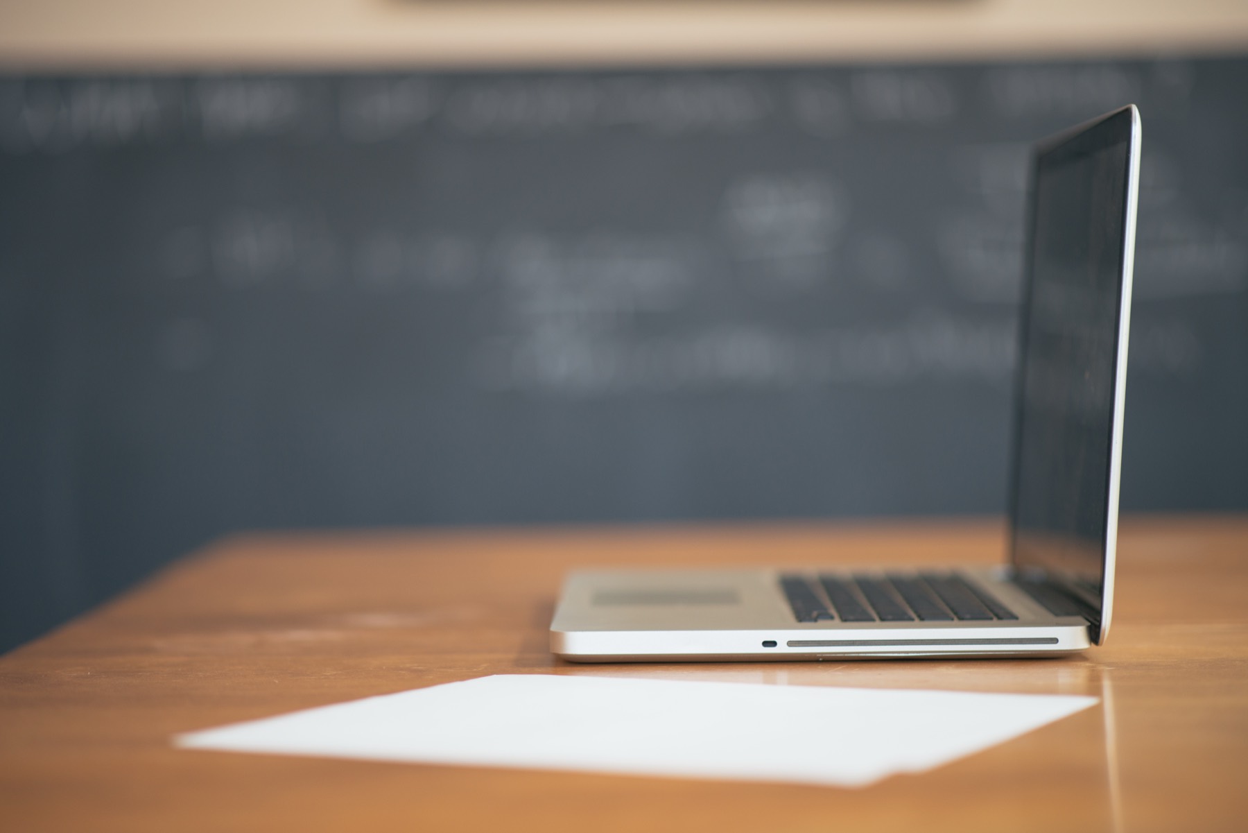 An open laptop resting on a desk in a simple workspace.